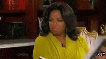 oprah winfrey is wearing a yellow robe and holding a book in her hand .
