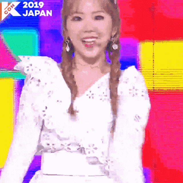 a woman in a white dress is standing in front of a colorful background with the year 2019 japan written on it .