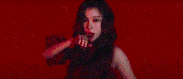 a group of people are standing in a dark room with a red light behind them .