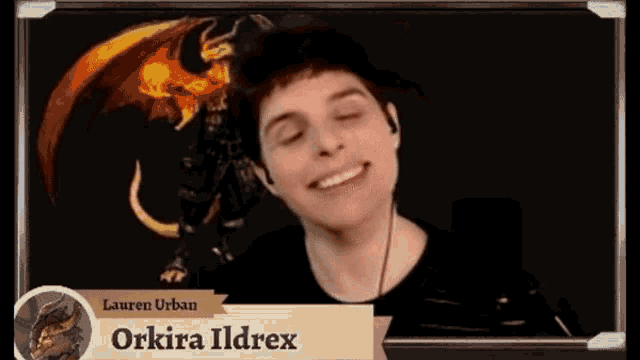 a woman is smiling in front of a picture of a dragon with the name orkira ildrex on it