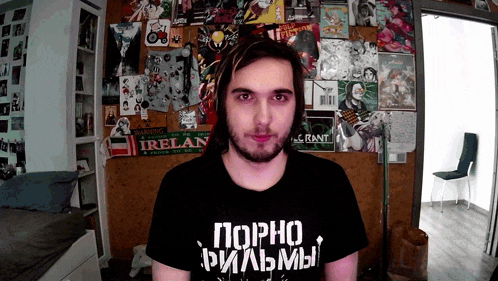a man wearing a t-shirt that says porno films looks at the camera
