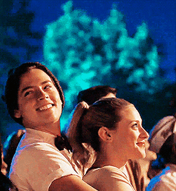 a man and a woman are sitting next to each other and smiling at the camera .