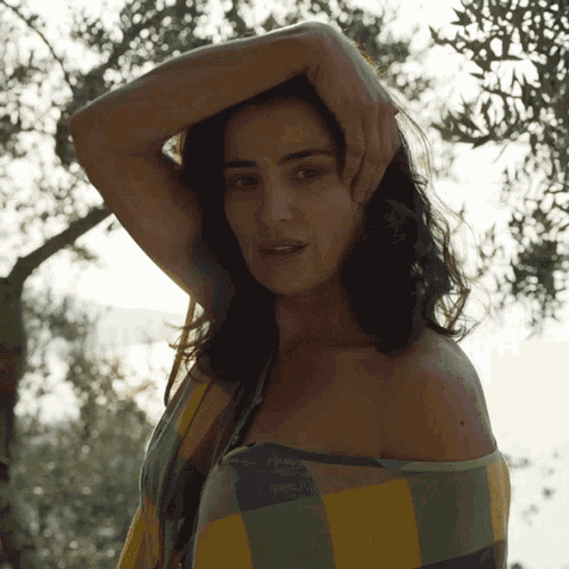 a woman wrapped in a plaid shirt is standing in front of a tree