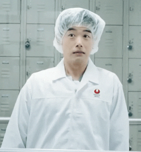 a man wearing a white lab coat with a red emblem on the sleeve