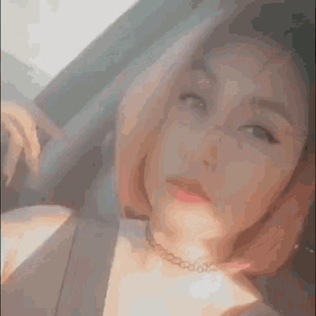 a woman with pink hair is taking a selfie in a car while wearing headphones and a choker .
