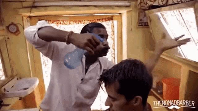 a man is getting his hair cut by a barber and the nomadbarber logo is visible