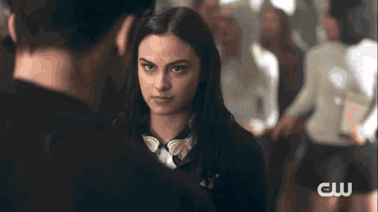 a woman is standing next to a man in a crowded room and looking at him .