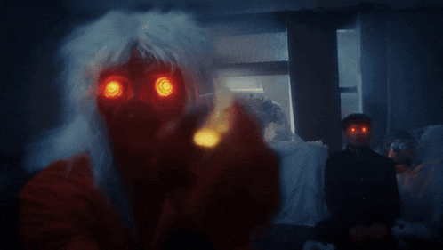 a person with red eyes is holding a candle in their hand