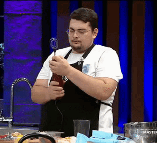 a man in an apron is holding a blender in a kitchen that says master on it