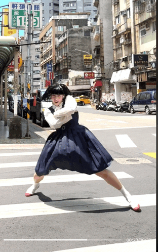 a girl in a blue skirt is crossing the street in front of a sign that says 13 on it