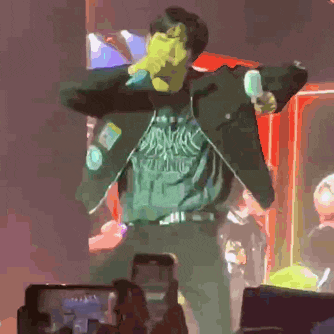 a man in a green shirt is holding a microphone