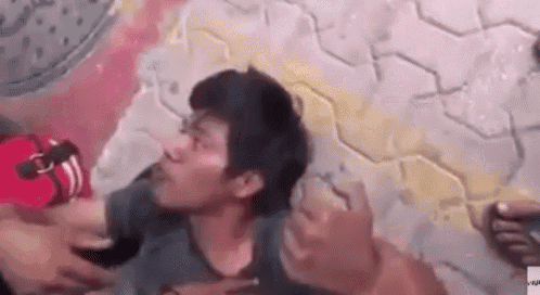 a man is laying on the ground with his head down while being held by a woman .