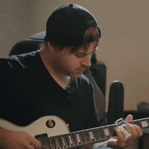 a man playing a guitar with a black hat that says nike on it