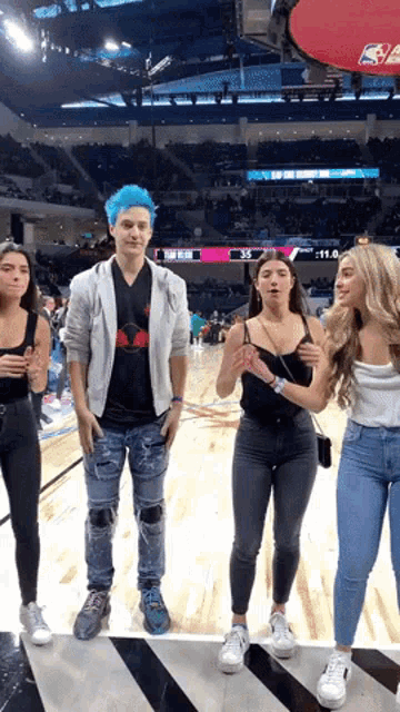 a group of people standing on a basketball court in front of a scoreboard that says nba on it