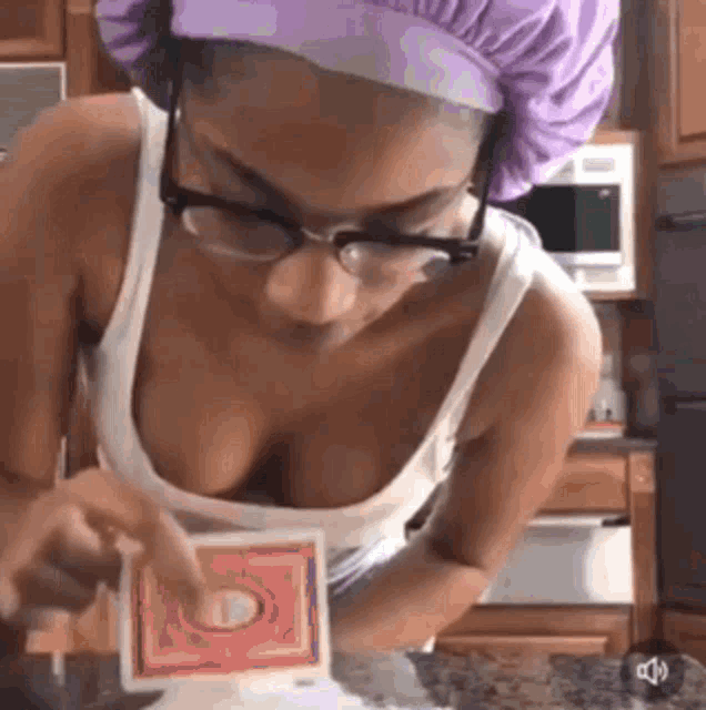 a woman wearing glasses and a purple hat is pointing at a playing card