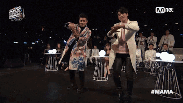 two men are dancing in front of a mnet banner