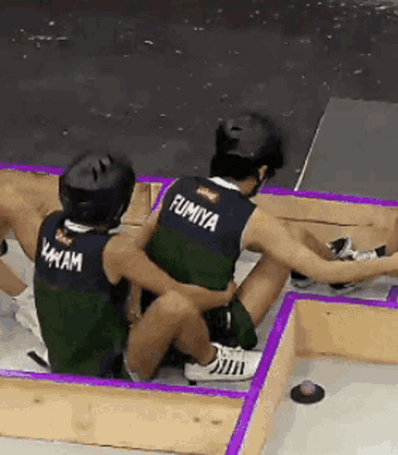 a man wearing a shirt that says fumiya sits next to another man