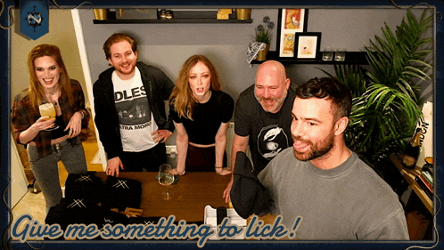 a group of people standing around a table with the words give me something to lick