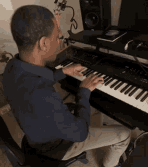 a man in a blue shirt sits at a keyboard