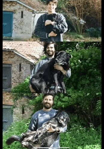 a man is holding a black dog in his arms in front of a brick building