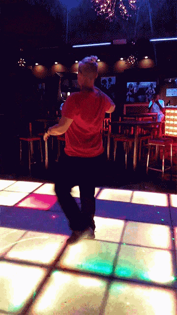 a man in a red shirt is dancing on the dance floor
