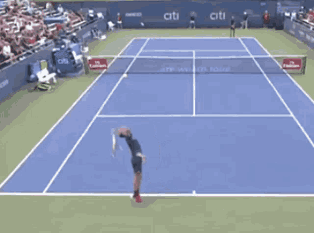 a tennis player stands on a court with a citi banner on the side