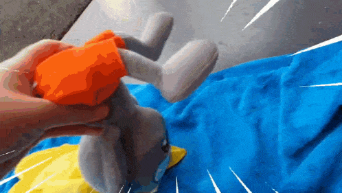 a person is holding a stuffed animal with orange gloves on it