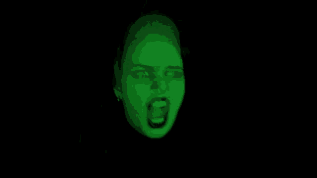 a close up of a woman 's face with a green light shining on it .