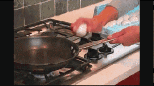a person cracks an egg into a frying pan on a stove