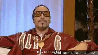 a man wearing a red jacket with the letter g on it is sitting on a couch with his arms outstretched .