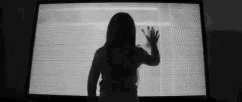 a black and white photo of a girl standing in front of a television screen .