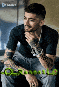a man with a lot of tattoos is sitting on a couch .