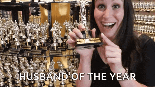 a woman holding a trophy that says " husband of the year "