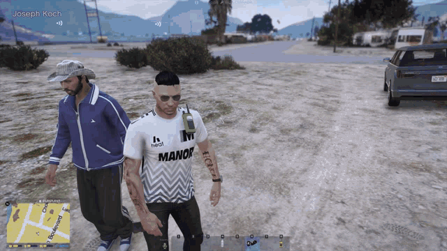 a man wearing a shirt that says manor walks with another man