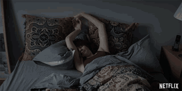 a woman laying in bed with a netflix logo on the bottom right