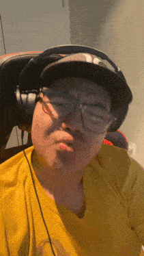 a man wearing headphones and a ny hat makes a face