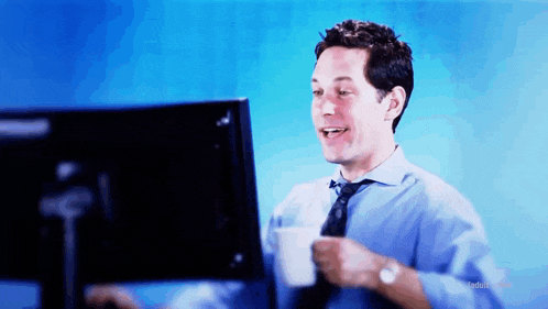 a man in a blue shirt and tie is holding a cup of coffee in front of a computer screen