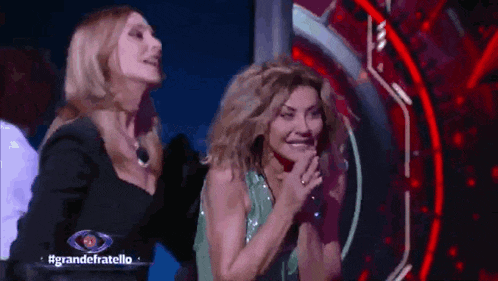 two women are standing next to each other on a stage and one of them is covering her mouth .