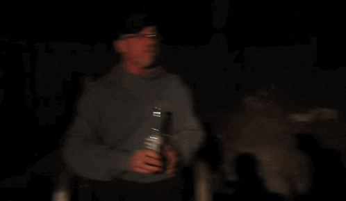 a man with a beard is holding a can of orange soda
