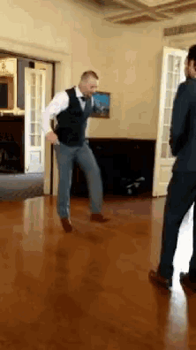 a man in a vest is dancing on a wooden floor