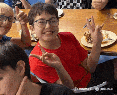 a boy in a red shirt and glasses giving a peace sign
