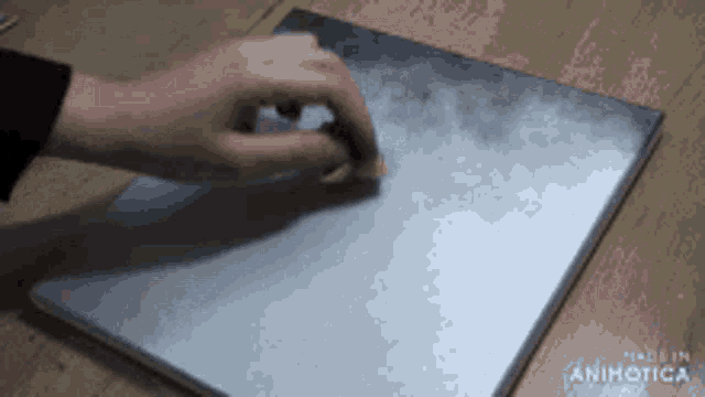 a person 's hand is cleaning a piece of metal that says made in animatica on it