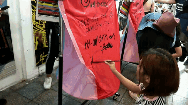 a woman writes on a red umbrella that says " i love you "