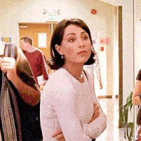 a woman stands in a hallway with a green exit sign above her head