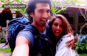 a man is carrying a woman on his back and they are taking a selfie .