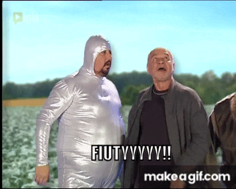 a man in a silver suit is standing next to another man and says fiutyyyy