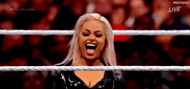 a woman is standing in a wrestling ring with her mouth open and smiling .