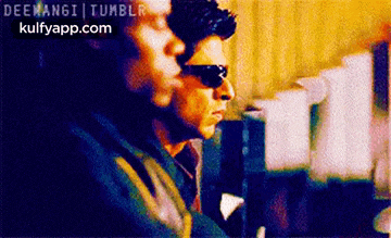 two men wearing sunglasses are standing next to each other in a room .