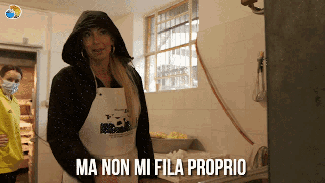 a woman wearing an apron that says ma non mi fila proprio is standing in a kitchen