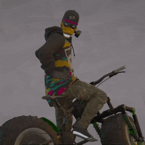 a person wearing a mask and a hat with the letter r on it is riding a bike